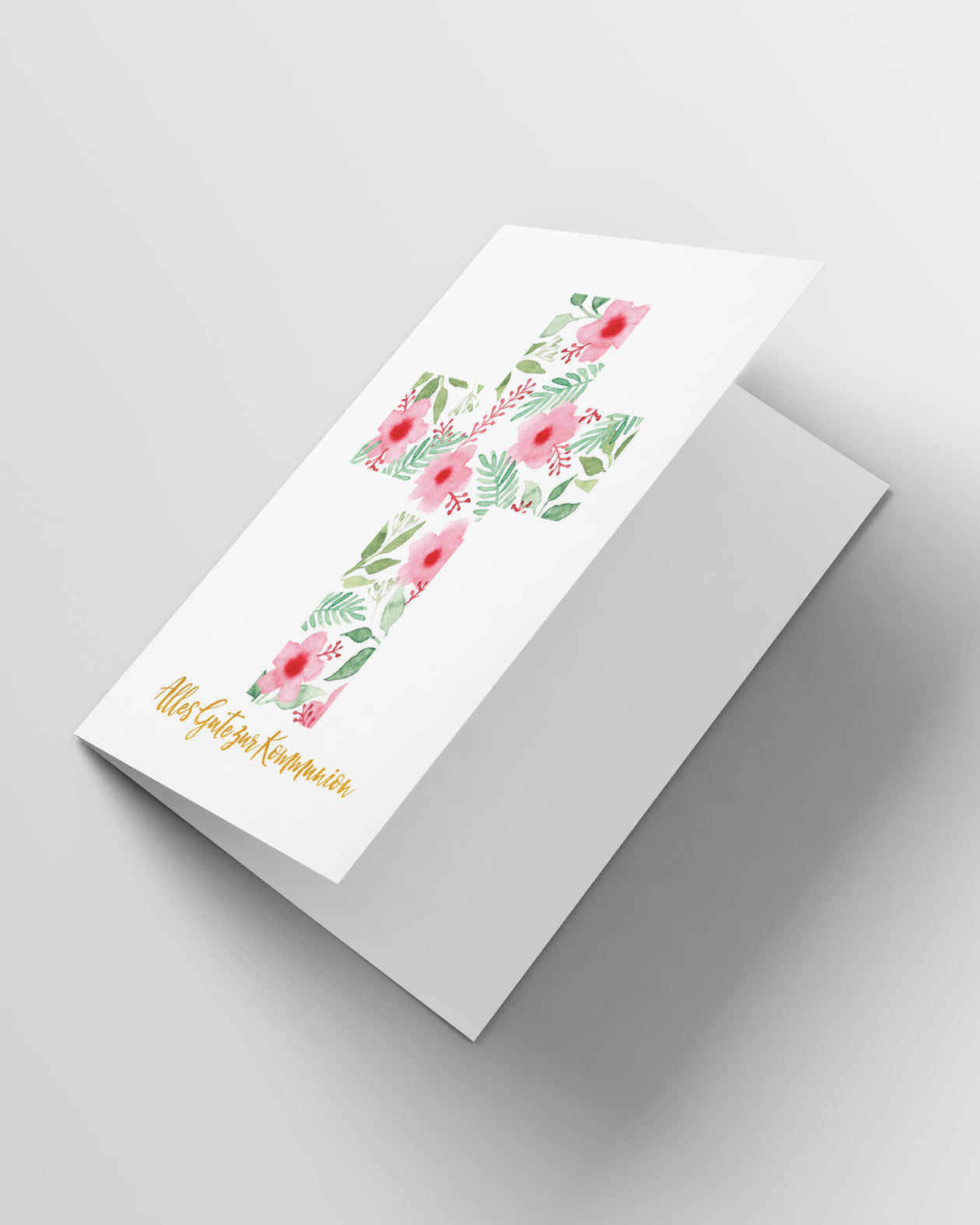 Grusskarte leicht geöffnet auf grauem Hintergrund. Außen ein Kreuz aus Aquarellblumen und -blättern auf weißem Hintergrund und goldener Text:Alles Gute zur Kommunion. Innen weißes Papier.