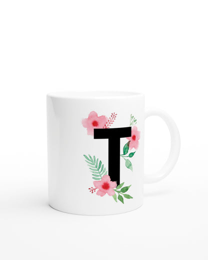 Weiße Keramiktasse mit schwarzem Buchstaben T und rosa-grünen Aquarell-Blumen