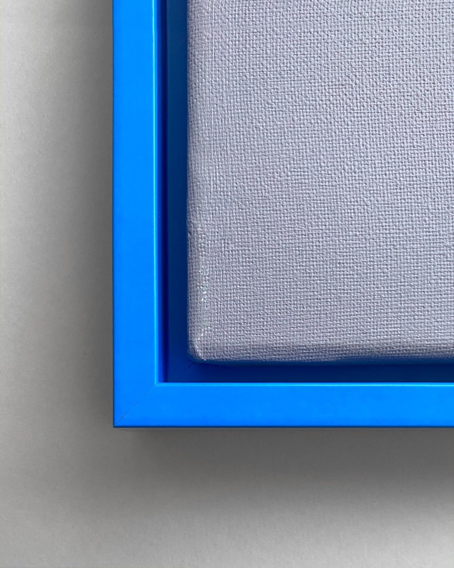 Detail  eines Schattenfugenrahmen in Neon Blau mit einer grauen Leinwand
