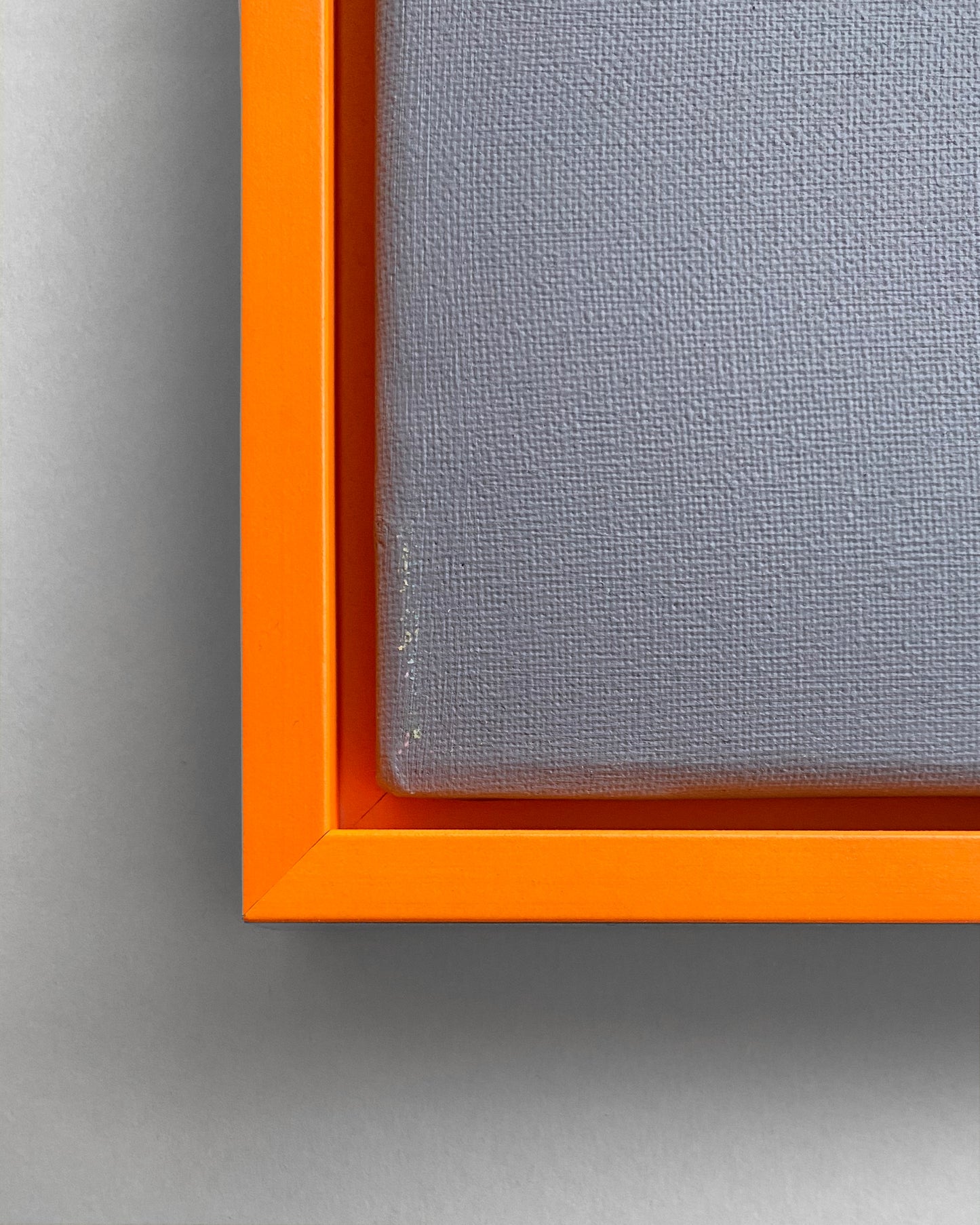 Detail des Schattenfugen-Rahmens in Neon Orange mit einer grauen Leinwand