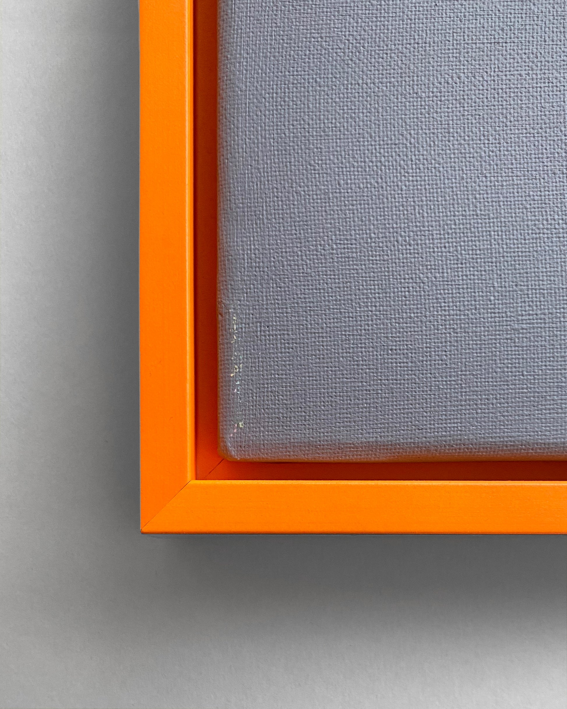 Detail des Schattenfugen-Rahmens in Neon Orange mit einer grauen Leinwand