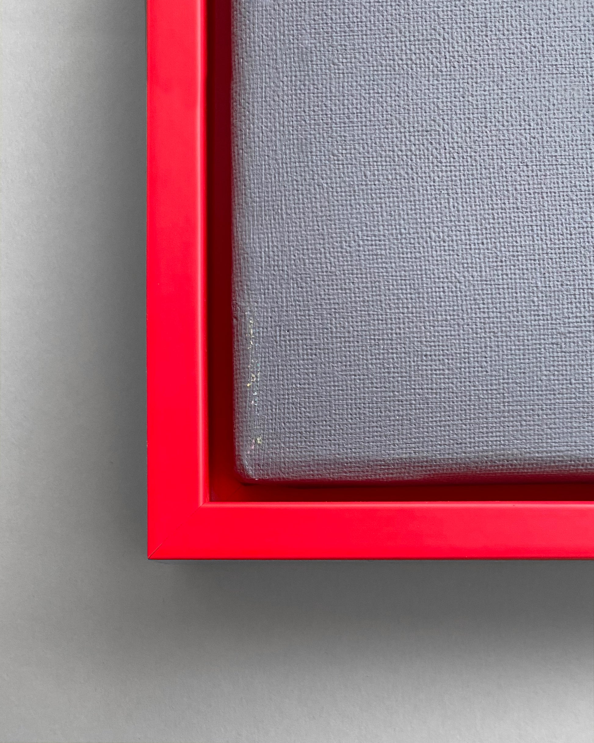 Detail des Schattenfugen-Rahmens in Neon Rot mit einer grauen Leinwand