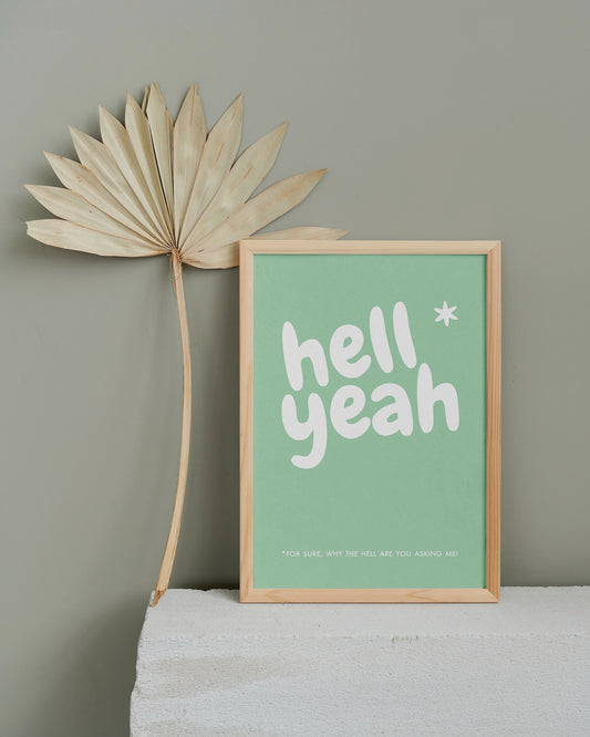 Poster "Hell Yeah" in Holzrahmen auf einem Steinsims mit Blattdeco.
