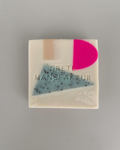 Seifenstück Constanze in Off-White mit geometrischen Einschlüssen in Neonpink, Hellblau mit Sprenkeln und Beige. 