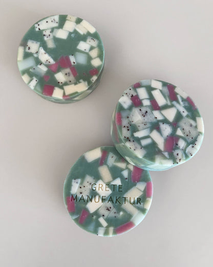 Drei runde Ette Seifen im Terrazzo-Design. Türkis mit geometrischen Fragmenten in Weiß und Lila.